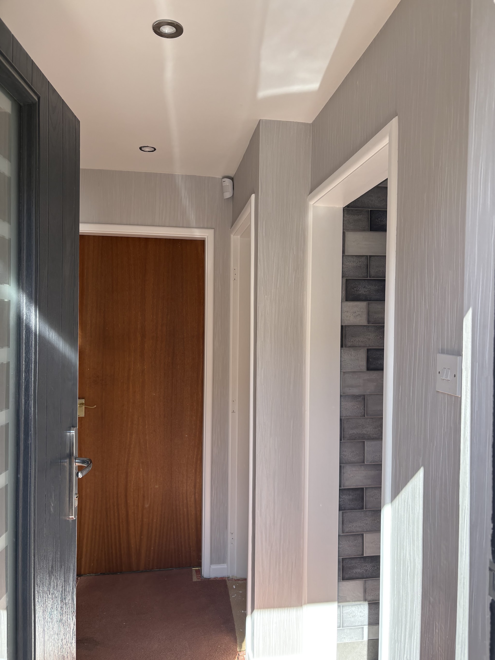 Freshly papered hallway with grey textured wallpaper and white woodwork