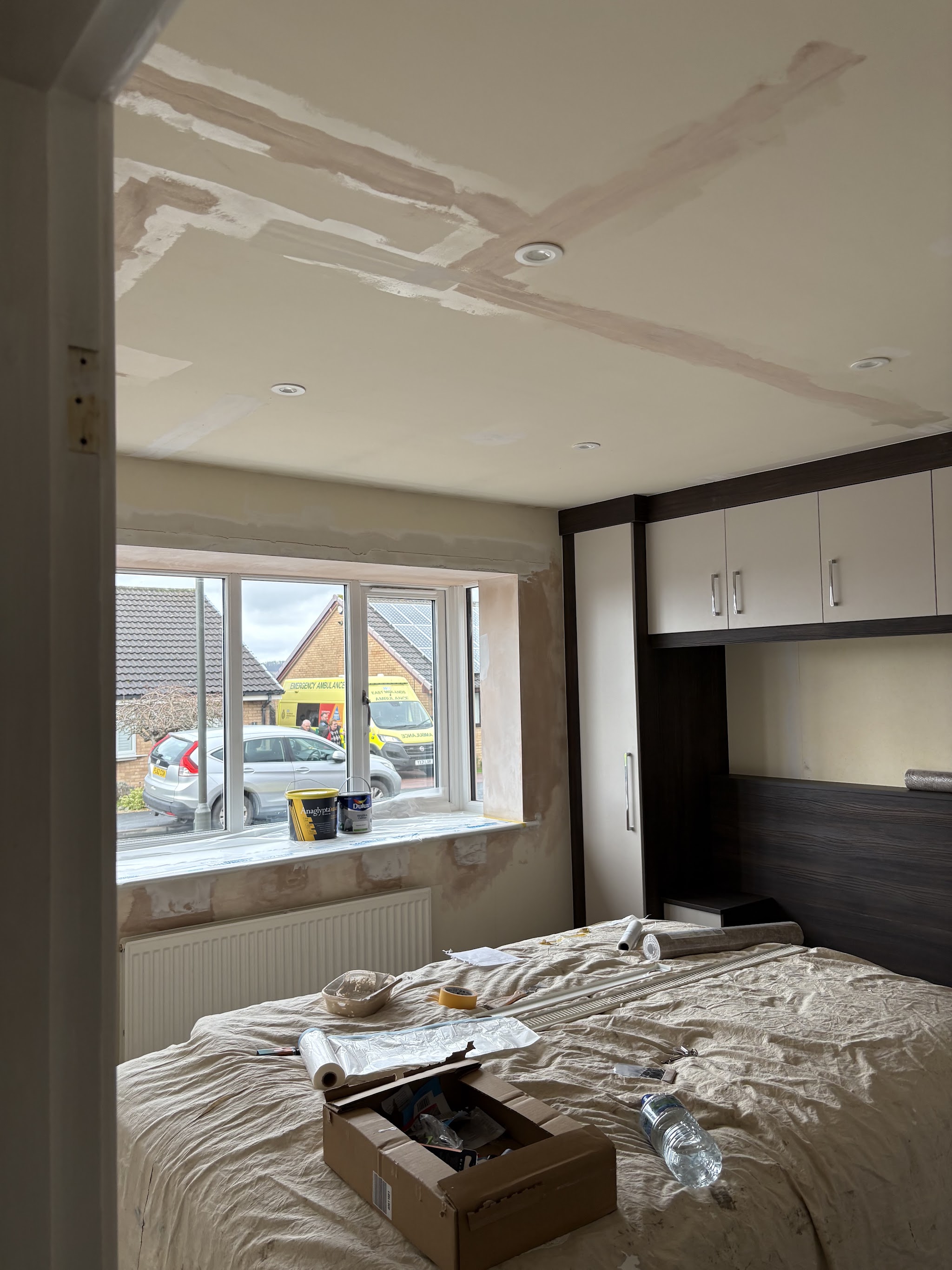 Bedroom before decorating, with filled plaster patches and covered furniture